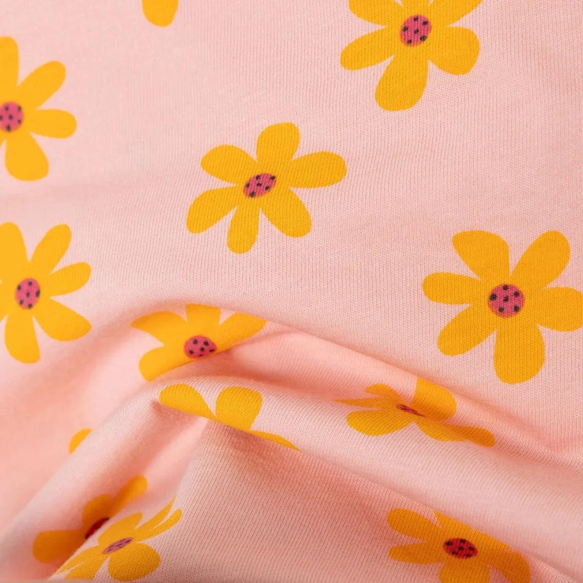 Salmon jersey baby T-shirt fabric close-up with orange-yellow flower print