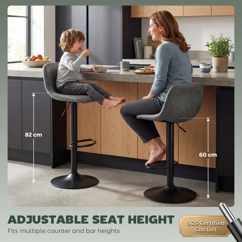 Two green swivel bar stools with footrest and adjustable height pedestal in kitchen