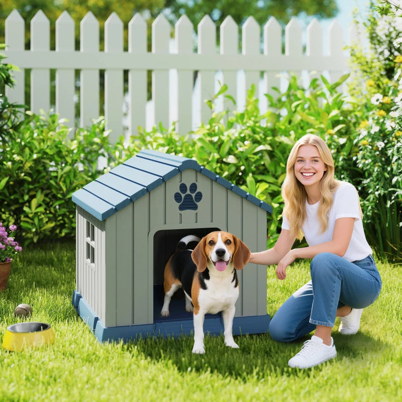 Grey outdoor dog house with blue roof and paw-print front panel; dog standing in yard