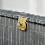 Grey bamboo laundry basket with lid, close-up of lining strap and button