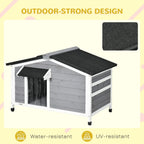 Grey wooden dog kennel with black roof panel and front access, supported by legs