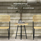 Round woven rattan-style side table with black metal legs on patio