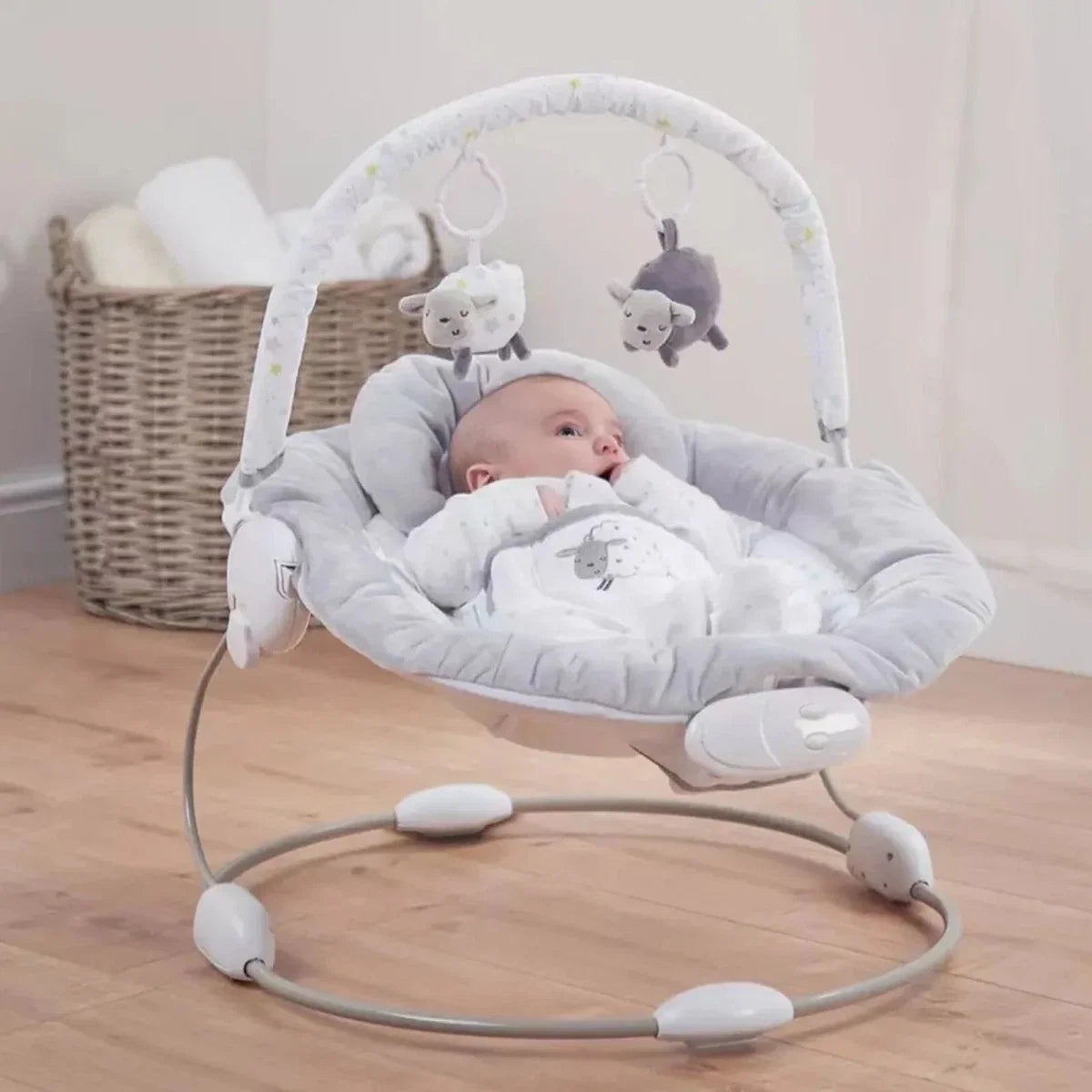 Grey baby bouncer with hanging plush toys and oval rocking base for sitting