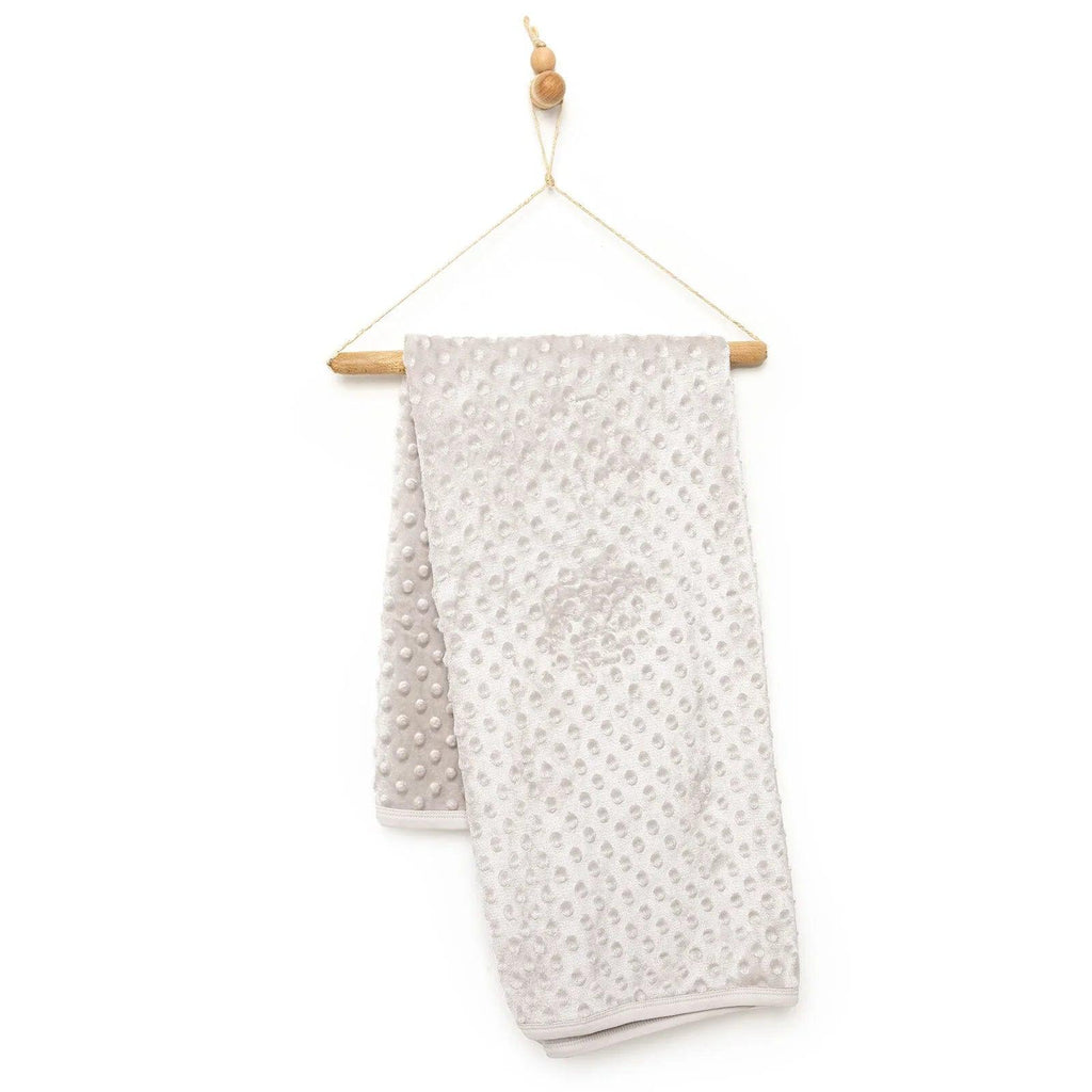 Beige fleece baby blanket with textured dot pattern and folded edge