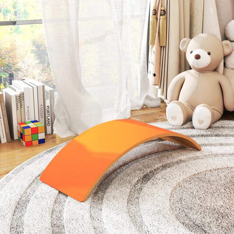 Orange curved wooden wobble balance board resting on a textured rug