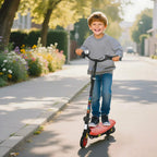 Red electric kids scooter with child rider, standing view on wheels.