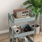 Light blue three-tier steel storage trolley with camera and media items on open shelves