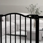 Black pet gate with arched top and side latch detail near a living room sofa