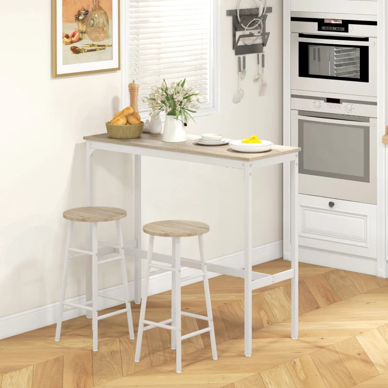 White bar table with two round light oak-tone stools in a kitchen with appliances.