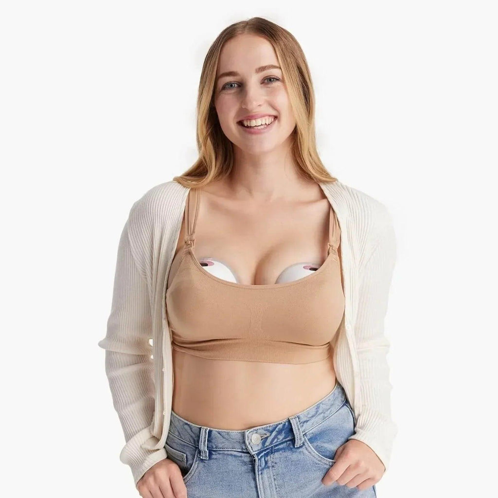 Woman wearing a beige wearable breast pump bra under a cardigan