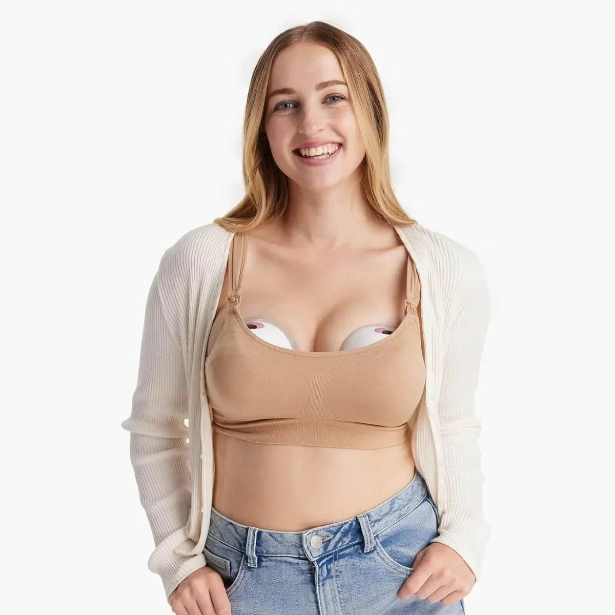 Woman wearing a beige wearable breast pump bra under a cardigan