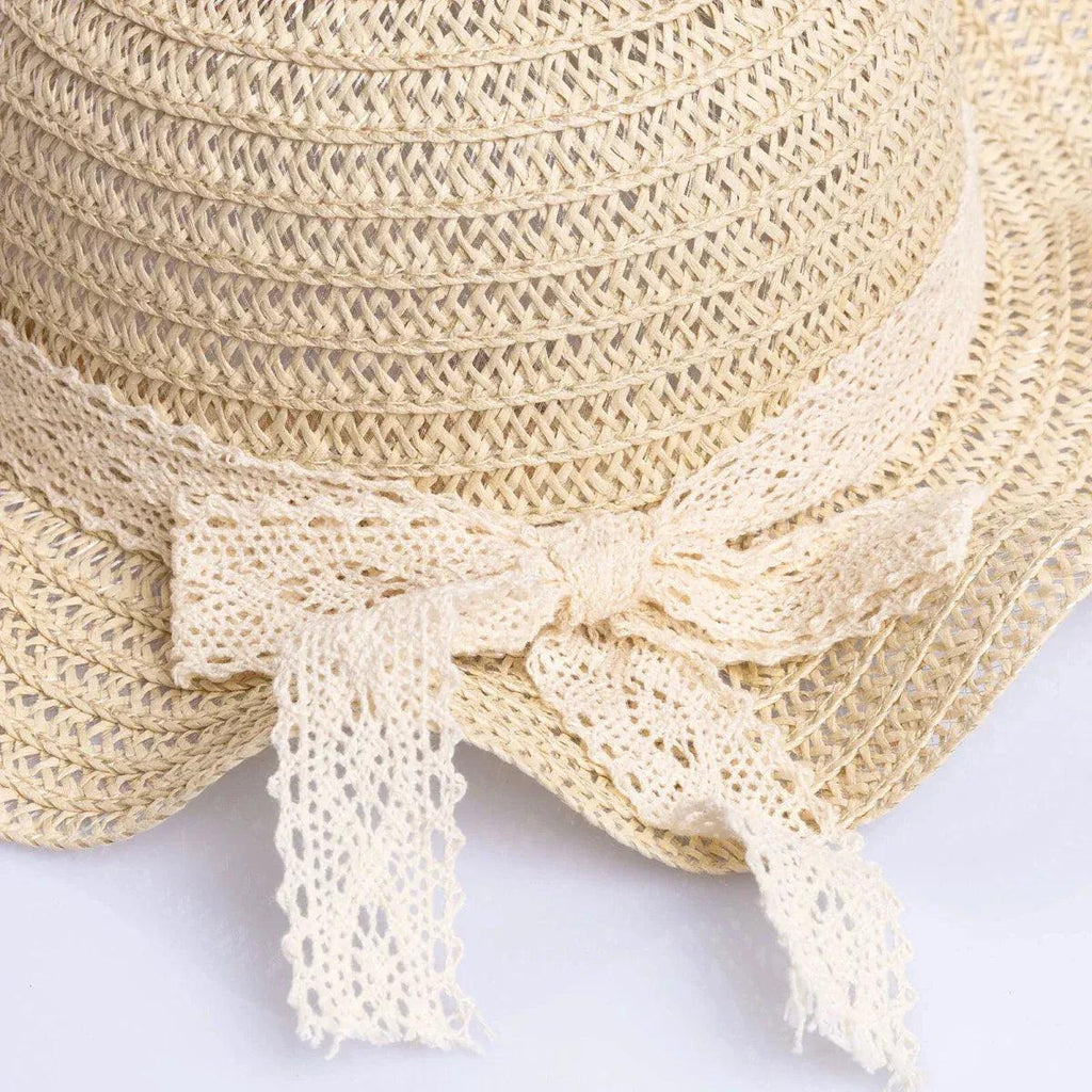 Ecru straw hat close-up with braided weave and ribbon trim at brim