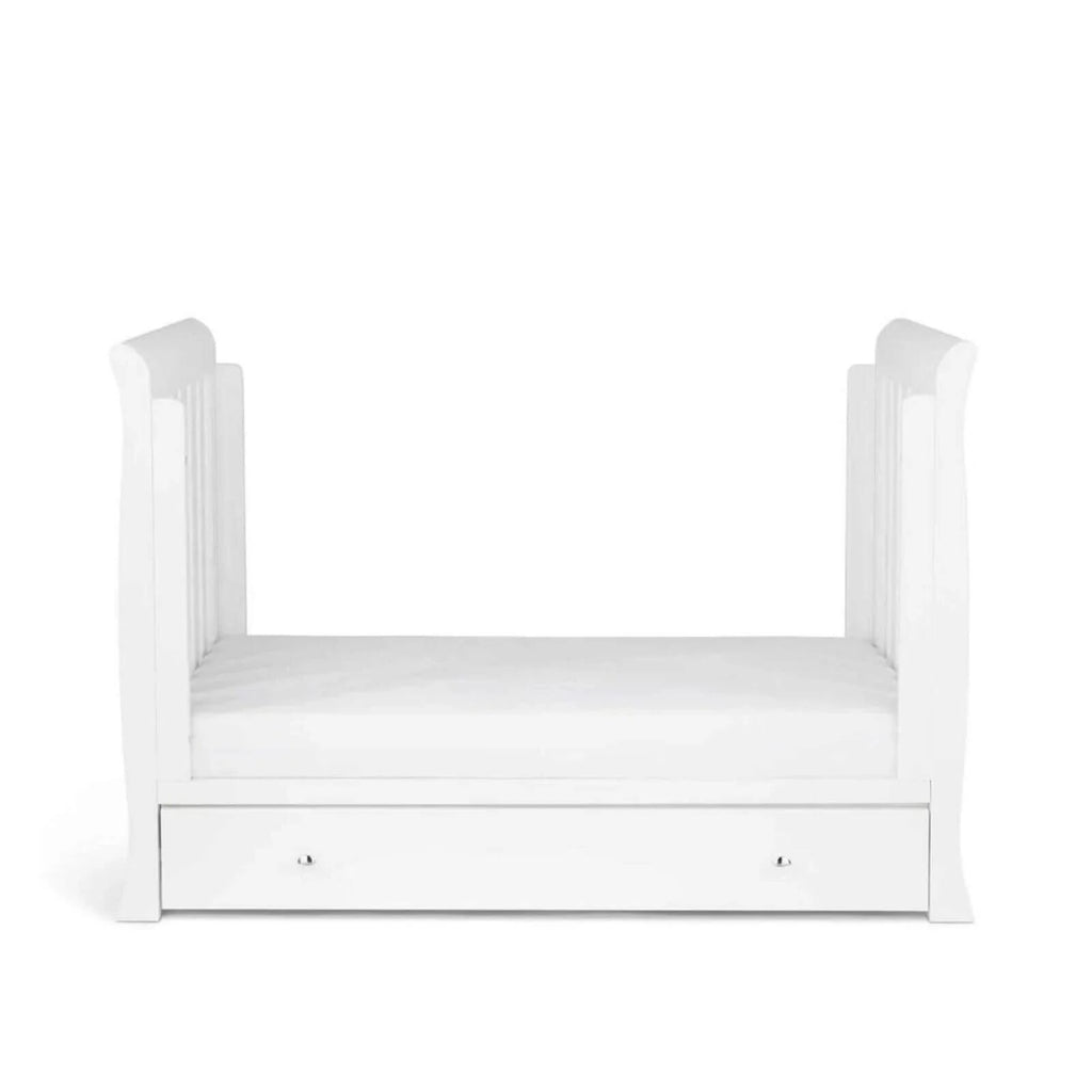 White mini cot with curved posts and a drawer under the mattress base