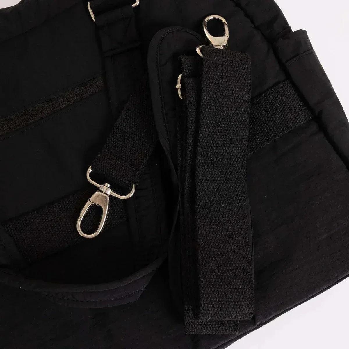 Black quilted shoulder bag side details with snap rings and fabric strap tab