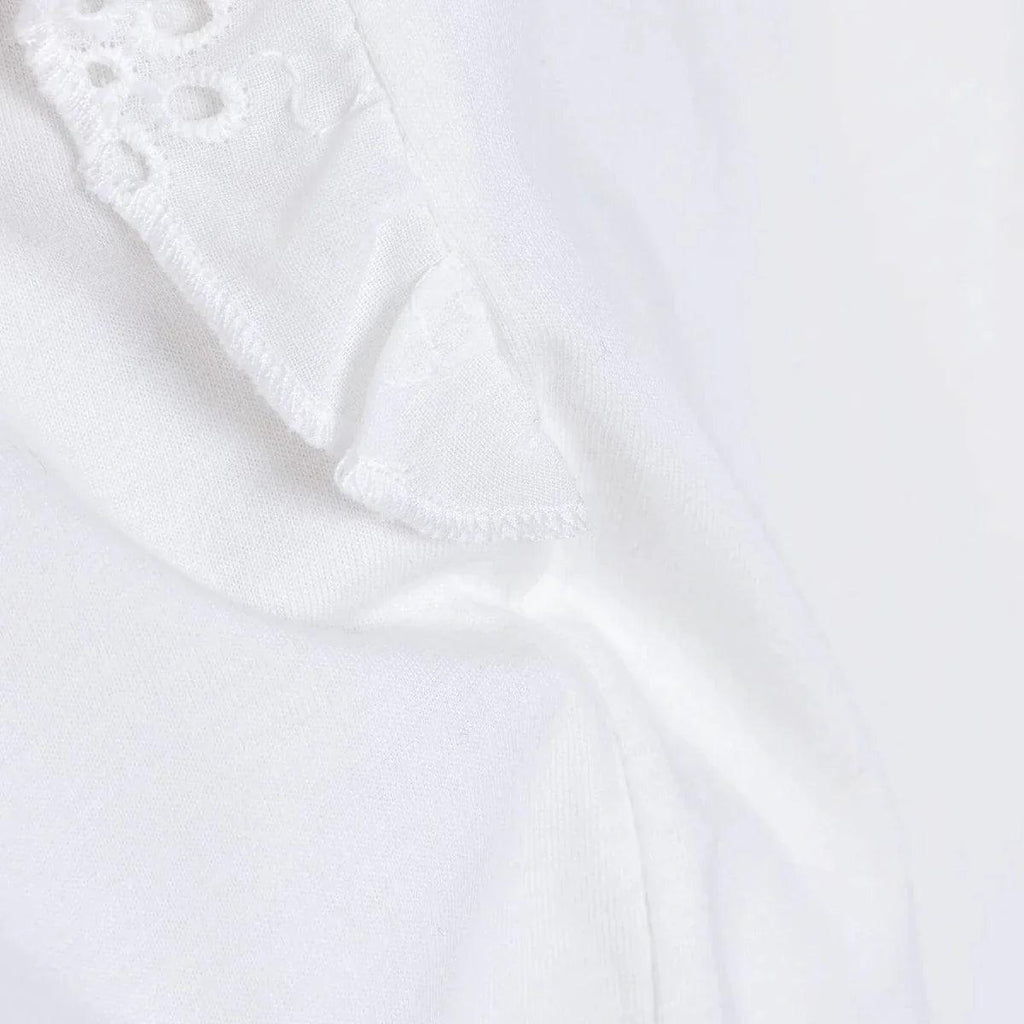 Off-white ruffled sleeve edge with subtle eyelet embroidery.