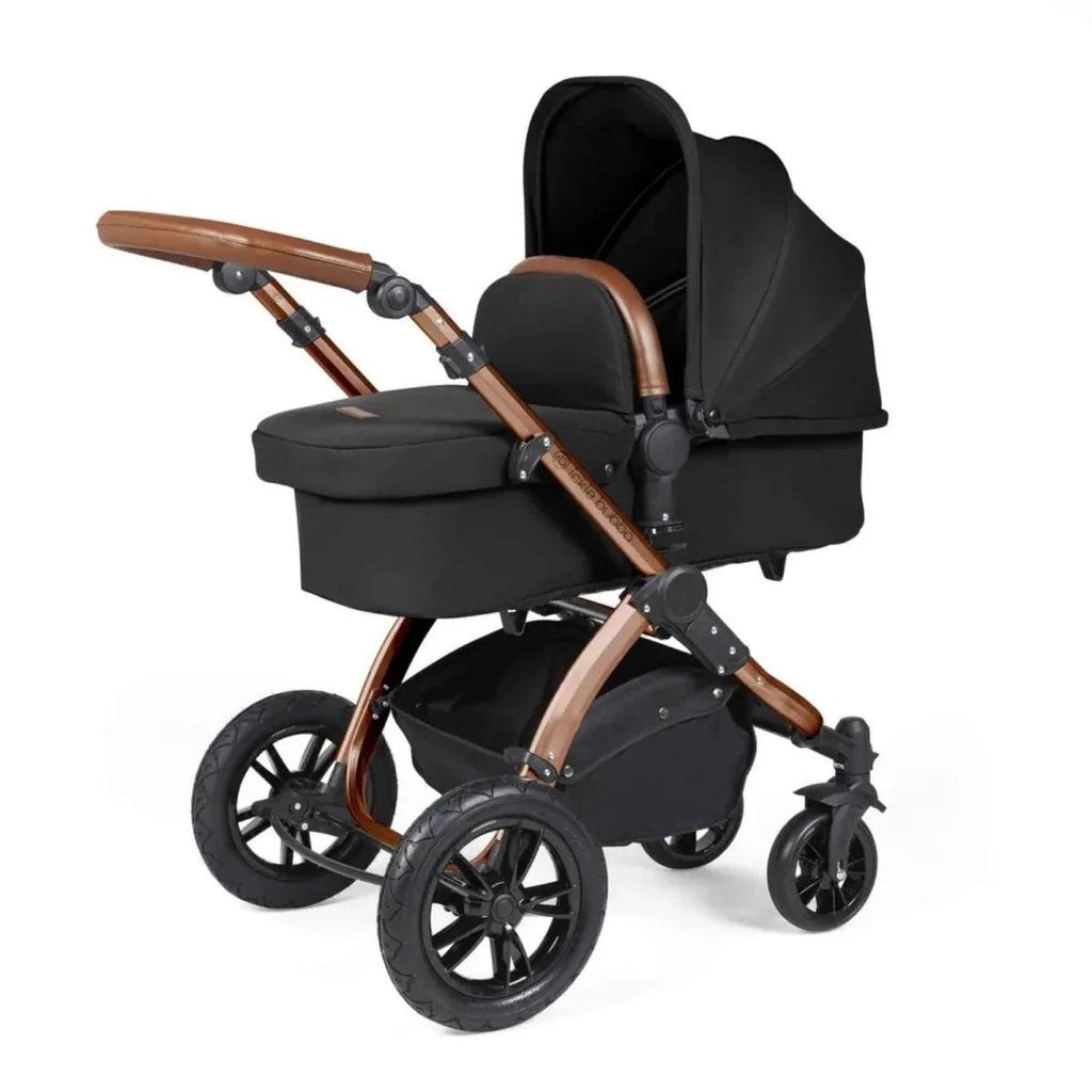 Black stroller with carrycot seat, bronze handlebar, and tan-trim details