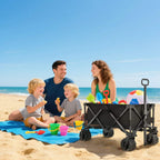 Black folding cargo wagon cart with pull handle and four rugged wheels on sand