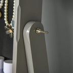 Grey cabinet door handle detail with pearl necklace hanging on the panel