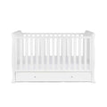 White cot bed with vertical slat rails and drawer base, without mattress.