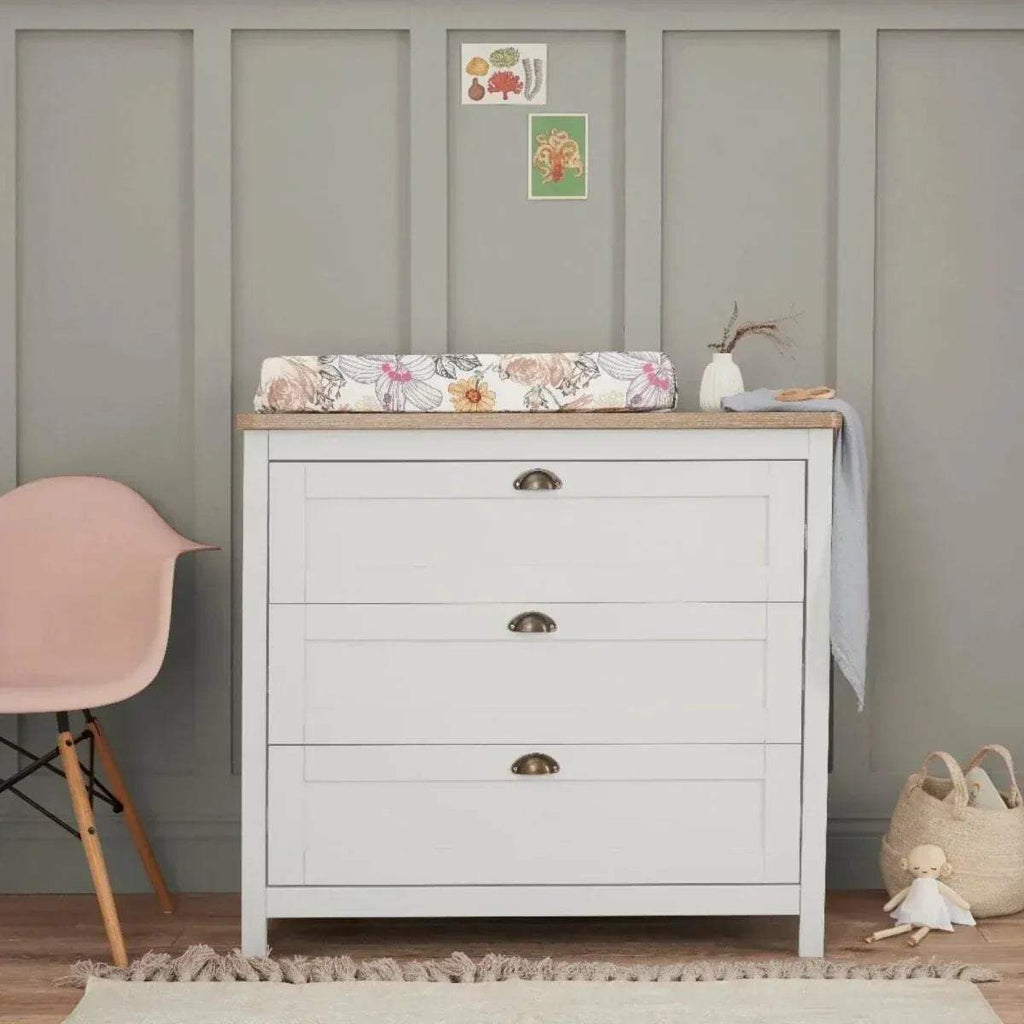 White baby chest changer with oak top, three drawers, and bronze metal cup handles