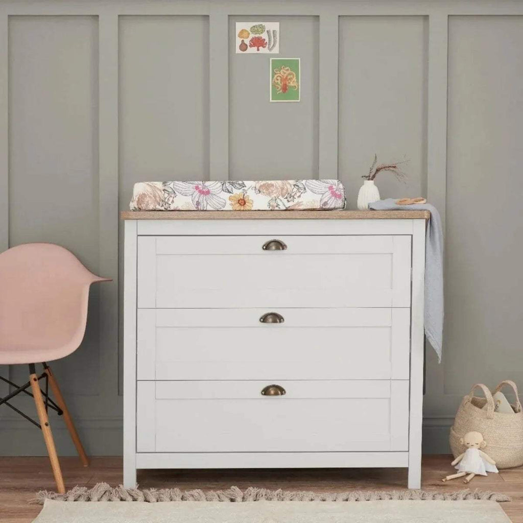 White dresser with three drawers and a fabric-covered top ledge
