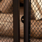 Black metal mesh fireplace screen close-up with door edge and latch hardware