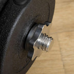 Close-up of black weight plate with threaded screw stud and steel rod end