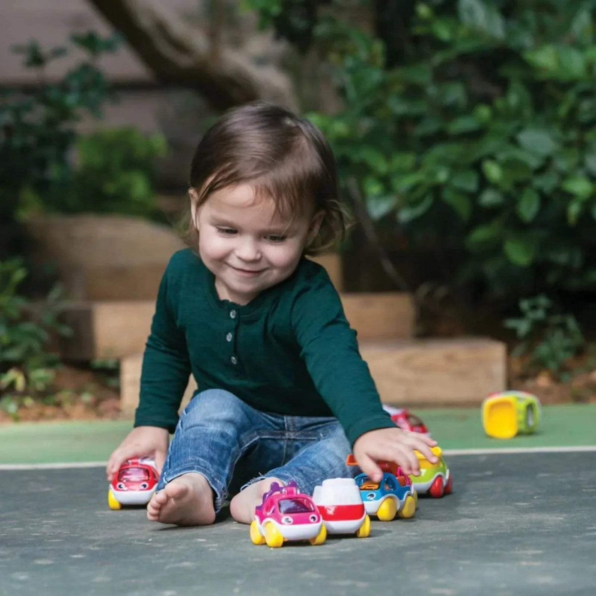 Assorted mini toy cars in red, purple, green, and yellow with smiling faces