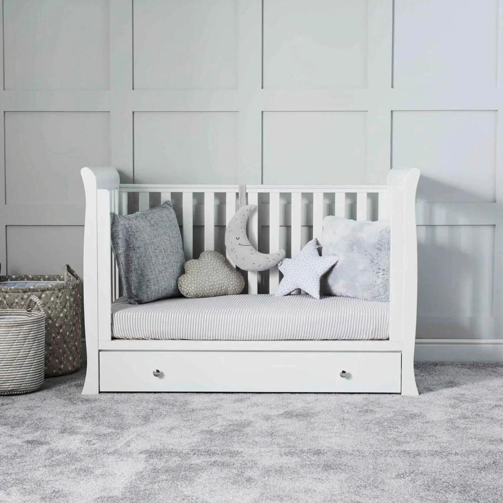 White mini cot bed with slatted rails, padded mattress and star/crescent pillows