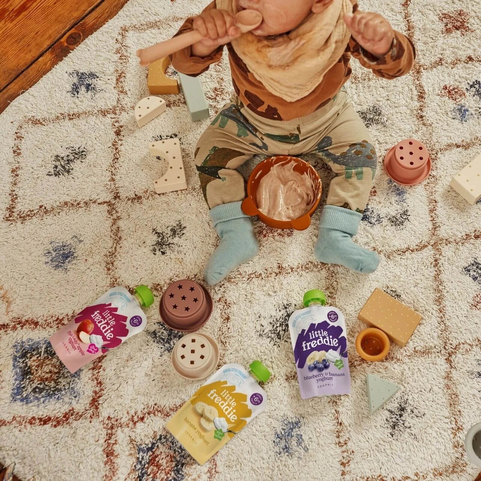 Multiple Little Freddie yogurt pouches scattered on play rug