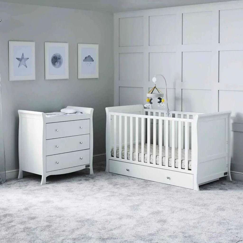 White nursery cot with matching dresser and vertical rail side