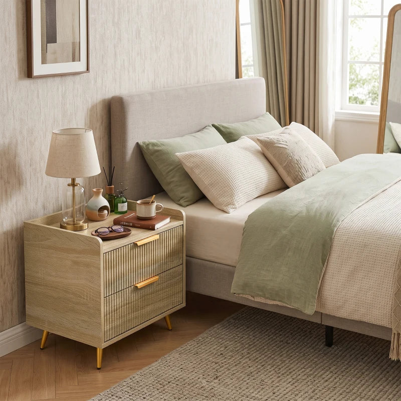Natural wood bedside table with two drawers and gold metal legs beside a sofa