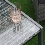 Dark glass tabletop with grey rattan weave, featuring a copper glass cup