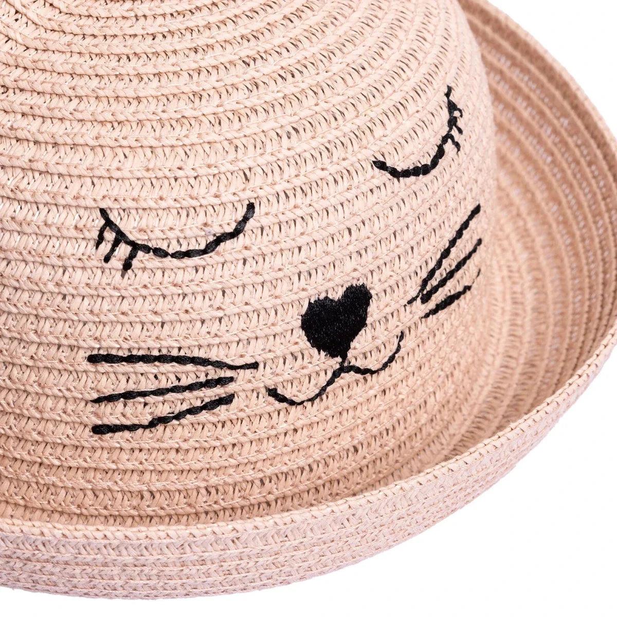 Light pink straw baby hat close-up: stitched cat eyes, whiskers, and nose