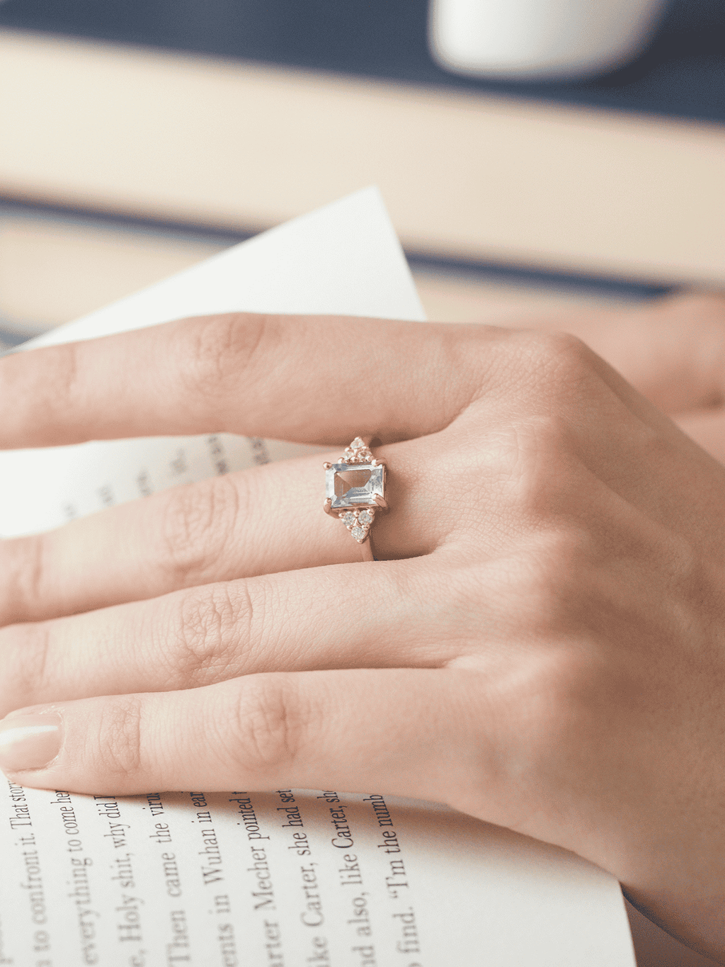 Gold vermeil ring on hand with emerald-cut blue topaz and small round side stones