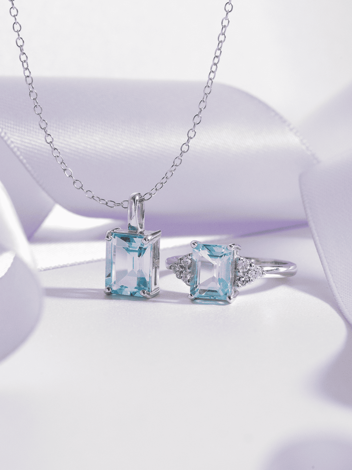 Sterling silver necklace chain with blue emerald-cut pendant and two blue gemstone rings