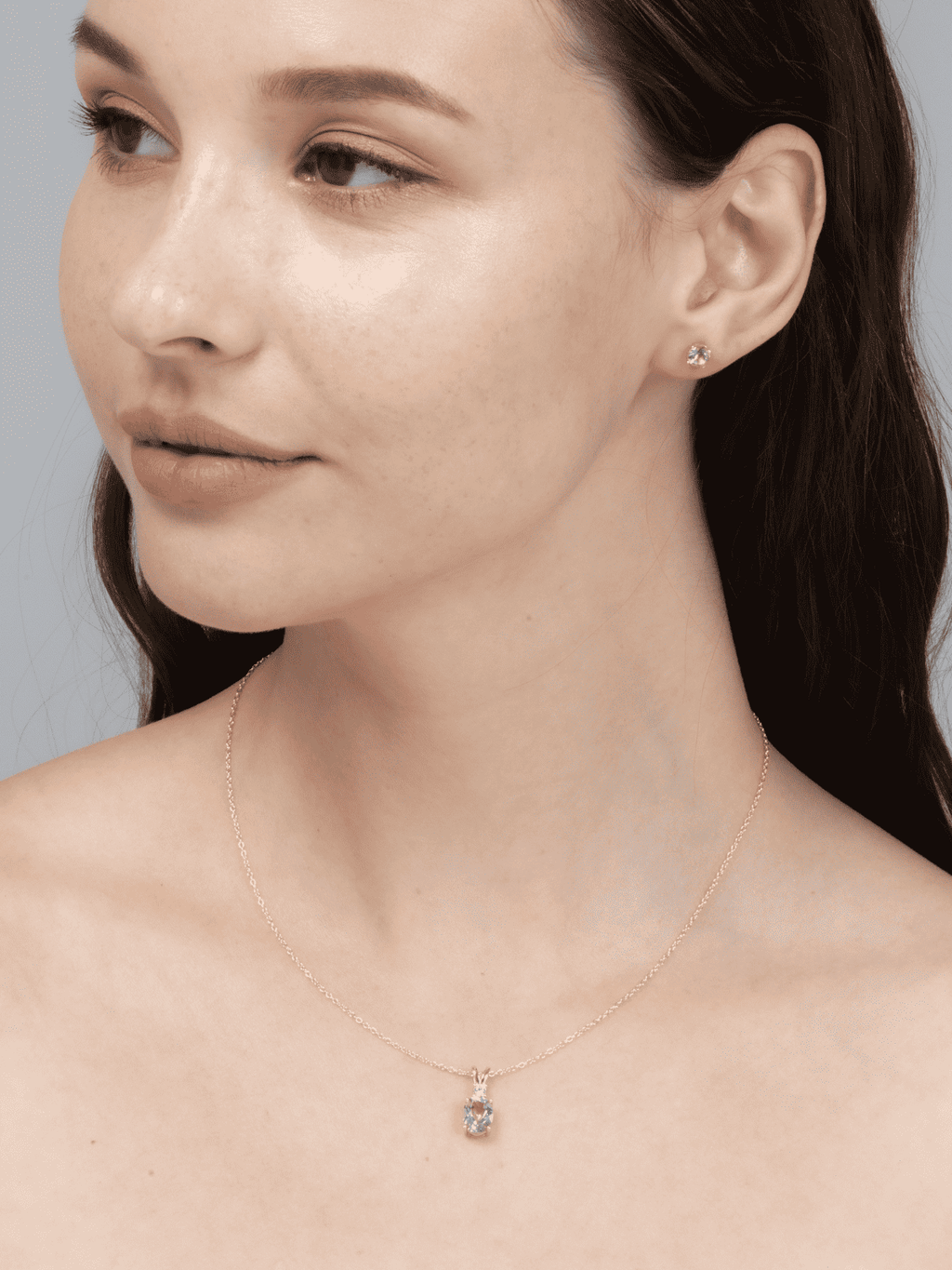 Gold-tone amethyst pendant necklace resting on the collarbone with small clear accents