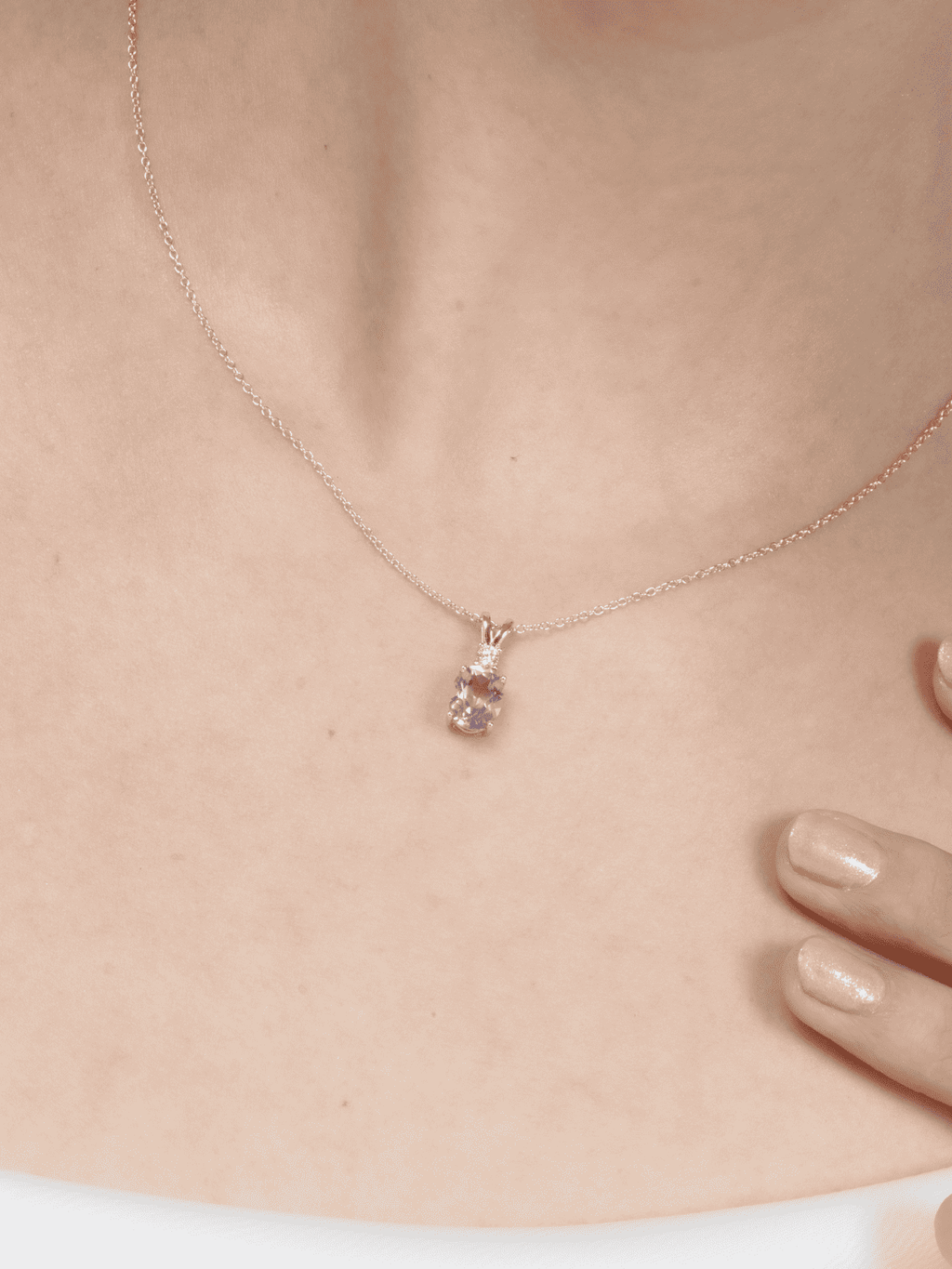 Rose-gold tone pendant necklace with small purple gemstone charm on neckline.
