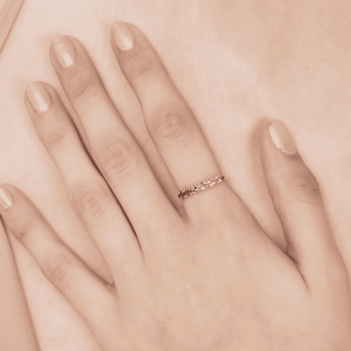 Pink gemstone eternity ring on open palm, showing a slim row of stones