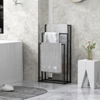 Black freestanding towel rack with three bars, holding gray towels in a bathroom.