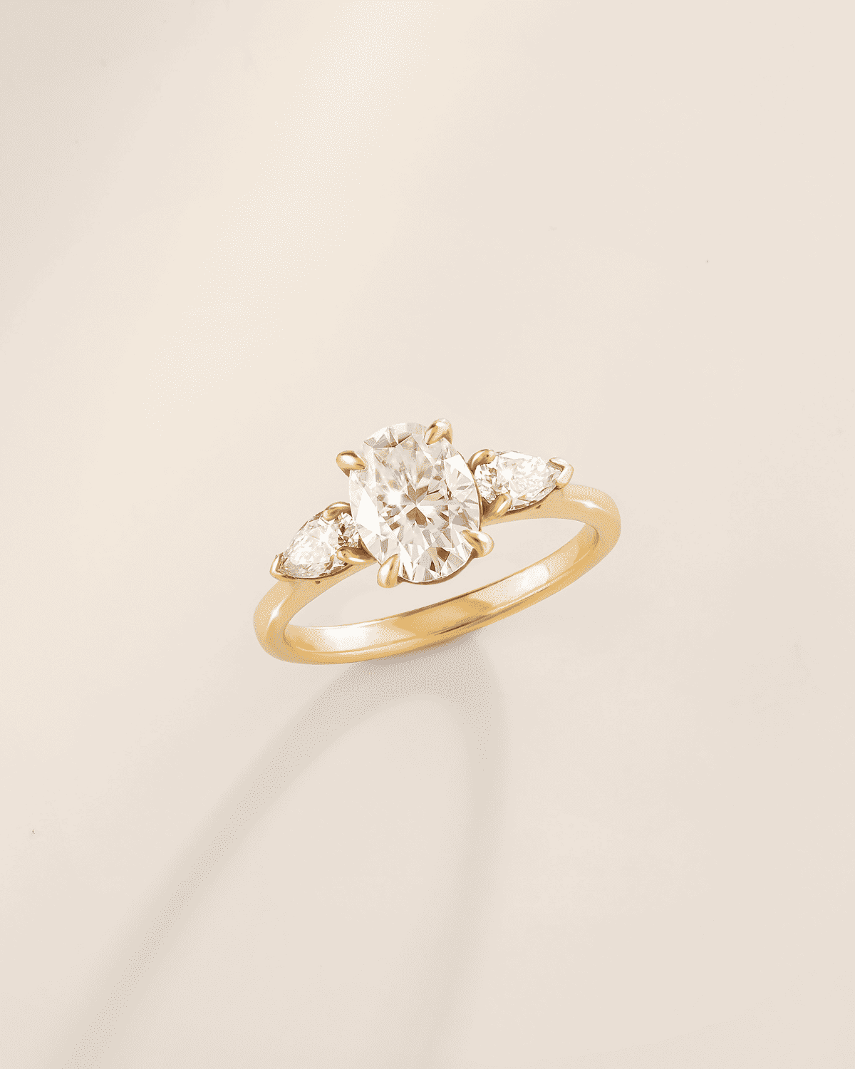Three-stone oval moissanite engagement ring with bezel-prong setting on gold-tone band
