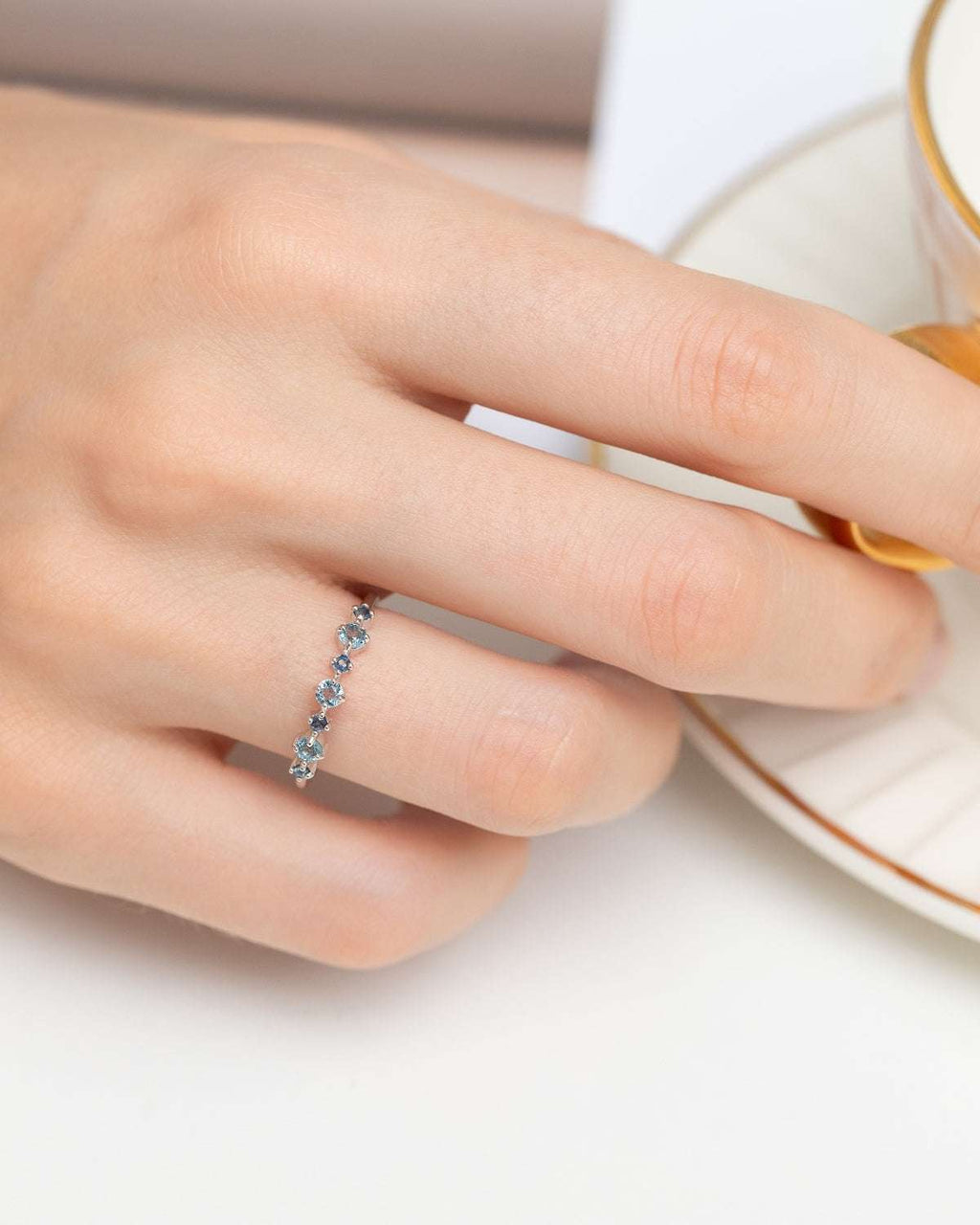 Sterling silver half eternity ring with blue oval stones on finger