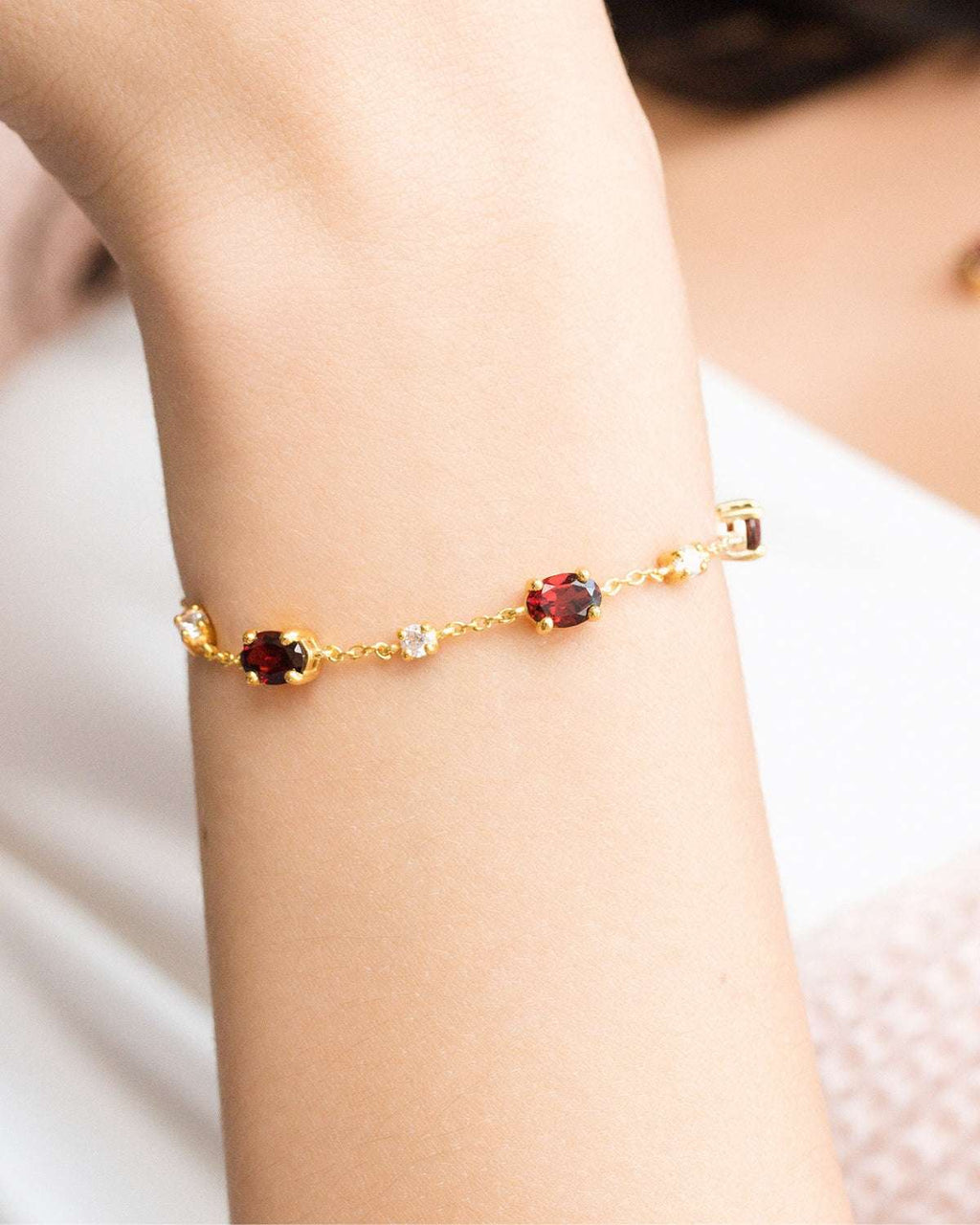 Close-up of a gold vermeil garnet bracelet on a wrist with oval red stones