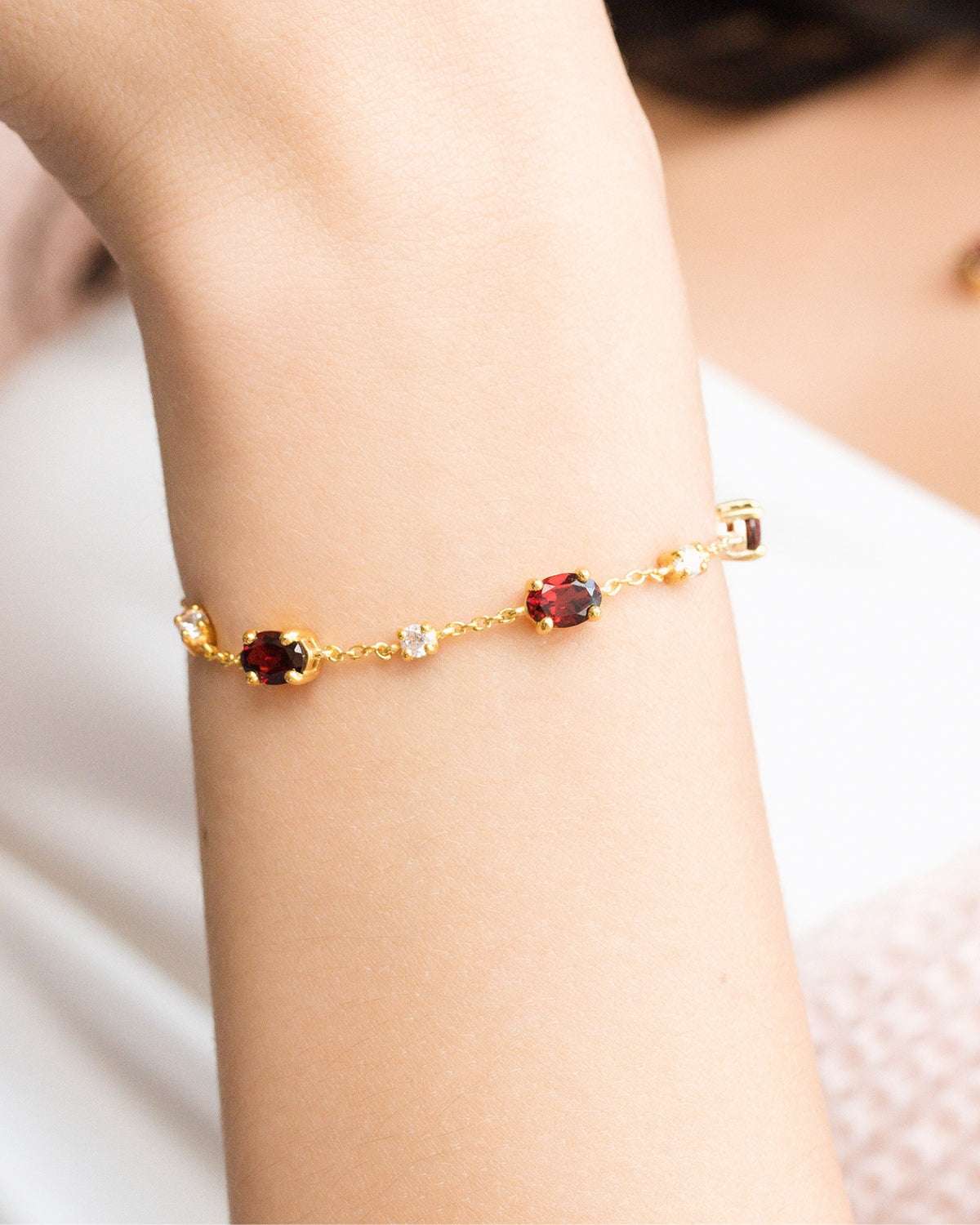 Close-up of a gold vermeil garnet bracelet on a wrist with oval red stones