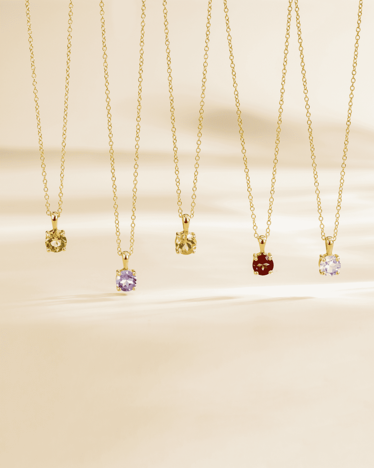 Group of gold vermeil pendant necklaces with colored solitaire gemstones, including light blue