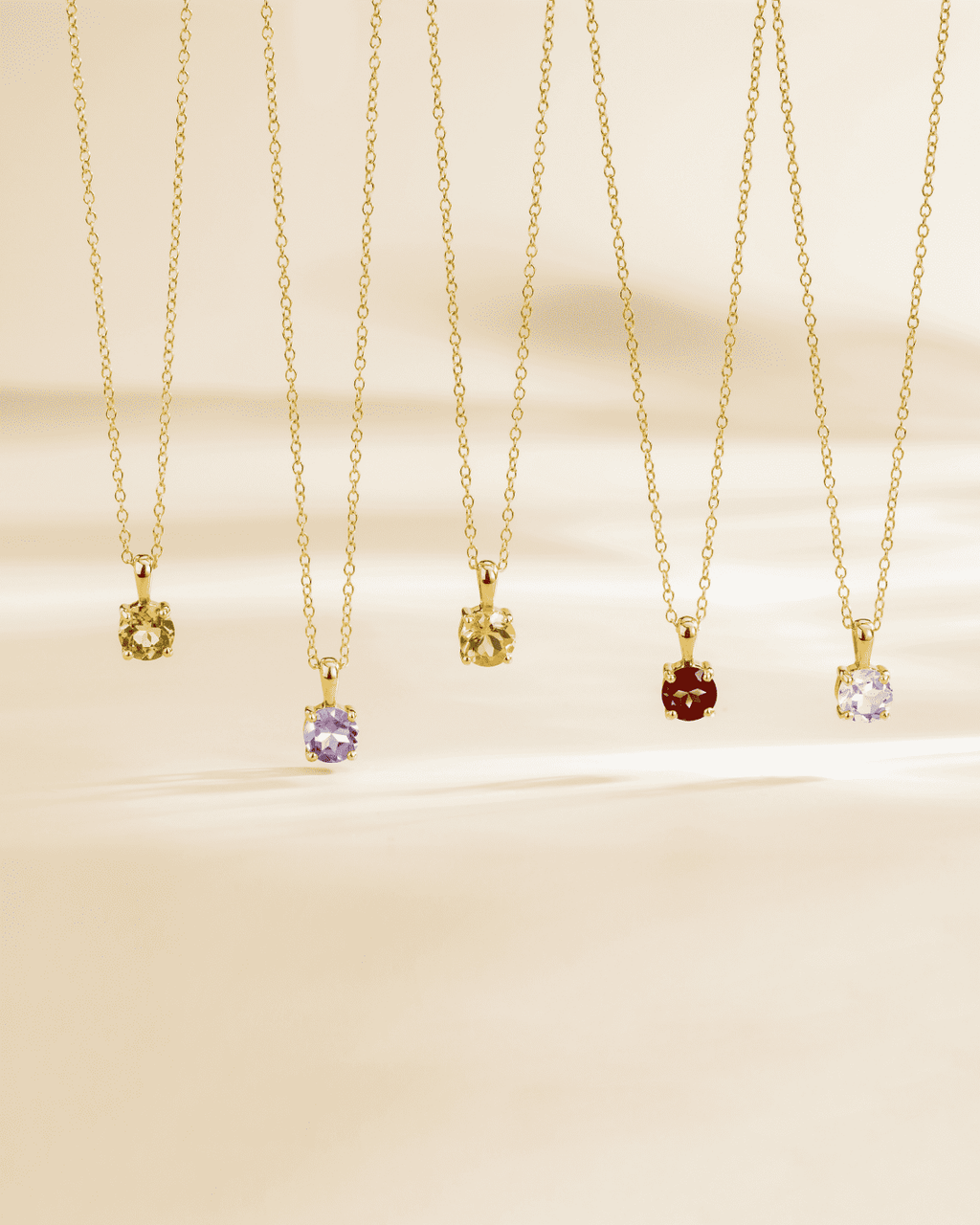 Set of gold solitaire pendant necklaces with faceted gemstones on thin chains