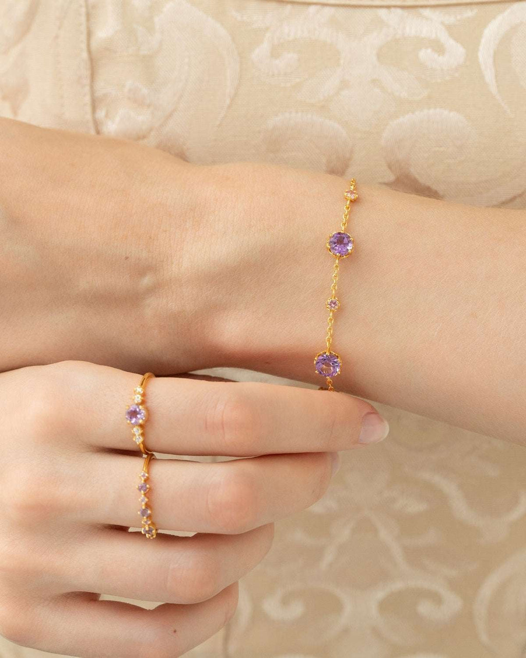 Gold vermeil five-stone ring with lavender center stone and clear stones on finger