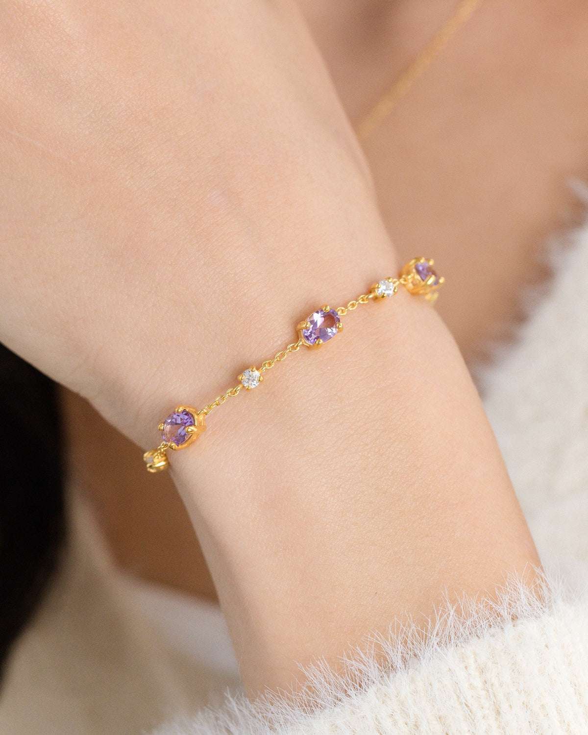 Close-up of gold vermeil bracelet with purple gemstones and small crystal accents.