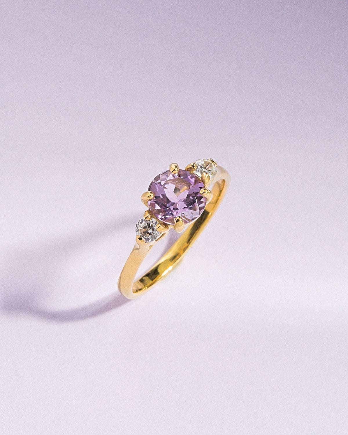 Lavender amethyst three-stone ring, side view showing gold-tone band and prongs