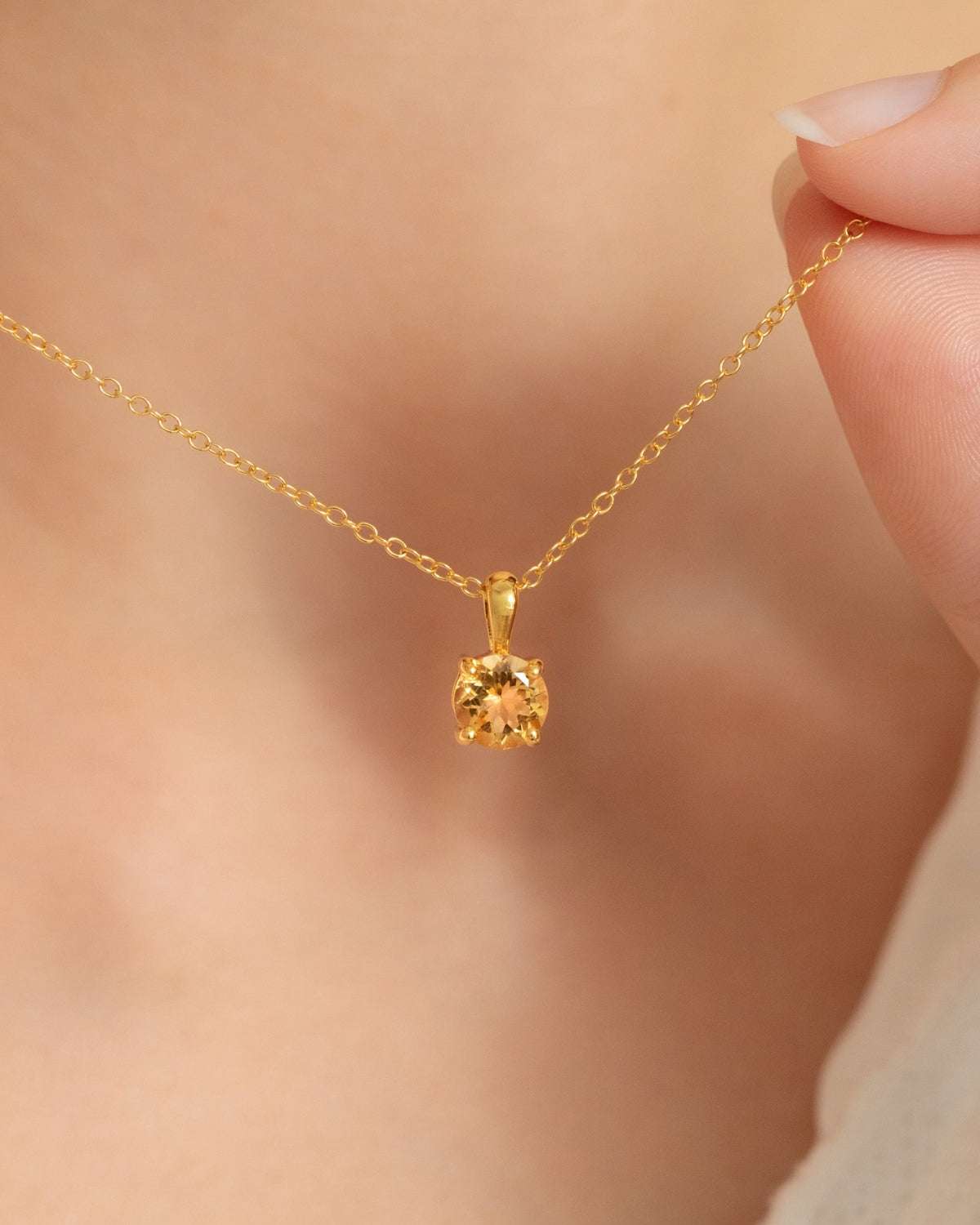 Citrine solitaire pendant necklace with a faceted round gemstone and gold chain